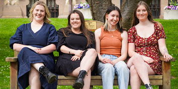 four women sitting on a park bench